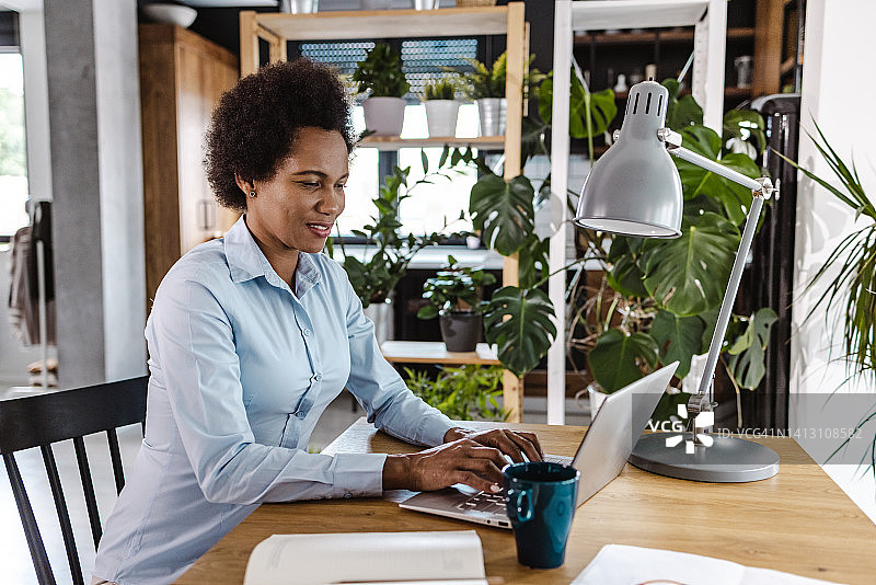 中年非洲裔美国女性在家里用笔记本电脑工作，专注于工作图片素材