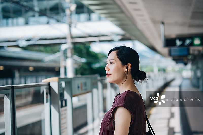 一名年轻的亚洲女性在城市乘坐地铁通勤，在地铁站台等待火车的肖像图片素材