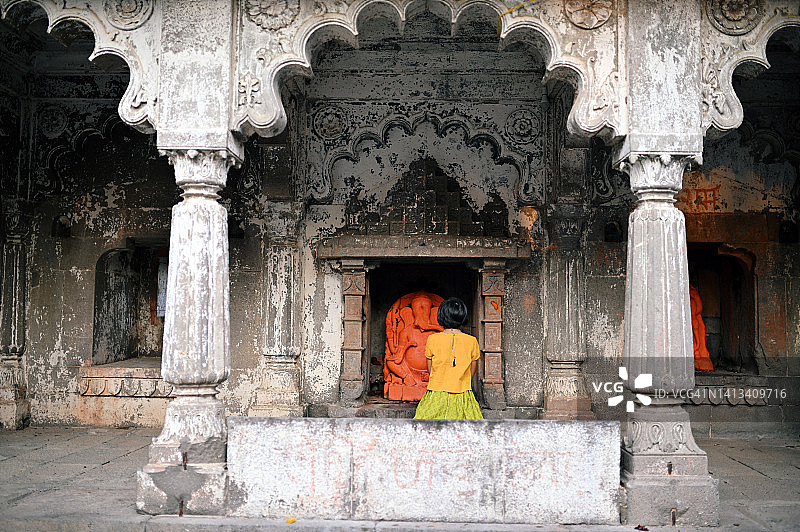 一个穿着印度传统服装的女孩在寺庙里坐着祈祷的背影。图片素材