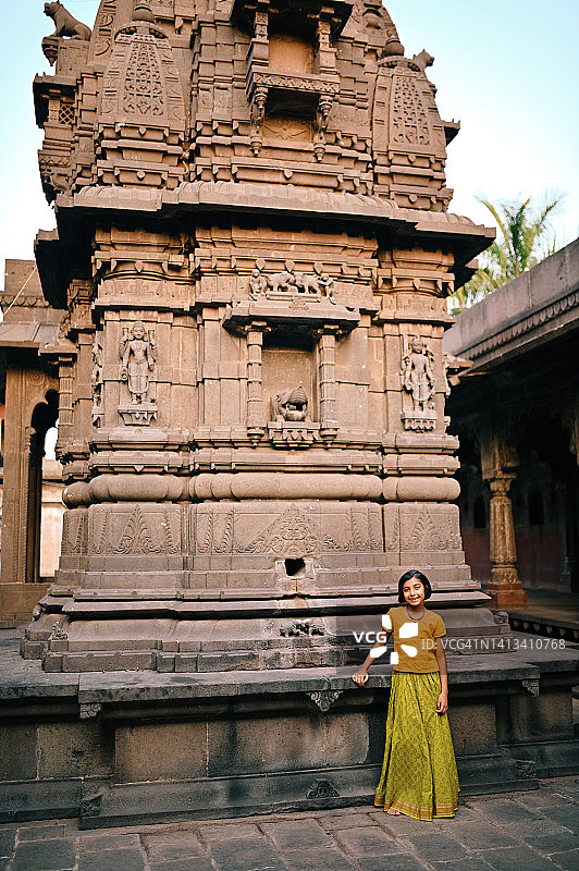穿着印度传统服装的可爱女孩站在一座古庙附近图片素材