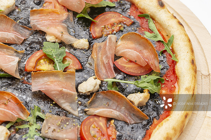 美味的披萨配上马苏里拉芝士，墨鱼墨汁，盛在一个木制的盘子里。前视图。图片素材