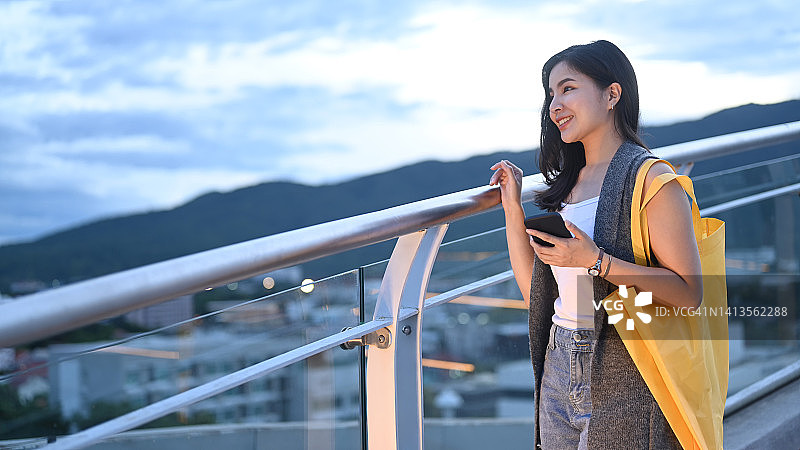 快乐的年轻女子站在屋顶露台与美丽的夜空背景。图片素材