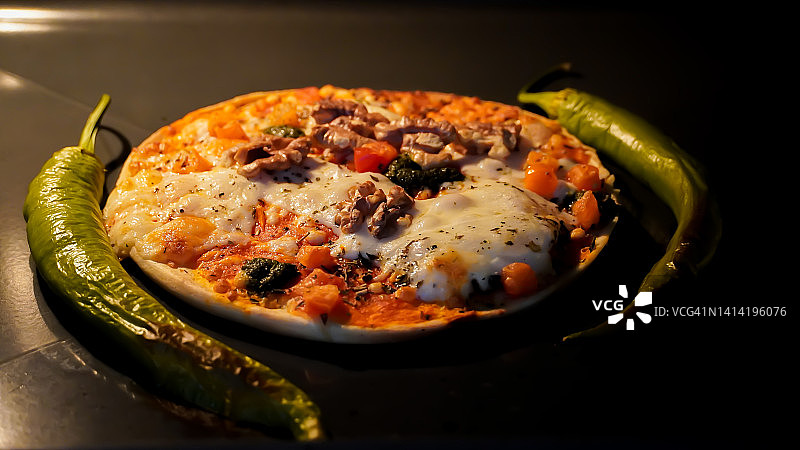 迷你披萨配马苏里拉芝士，坚果和辣椒在烤箱里图片素材