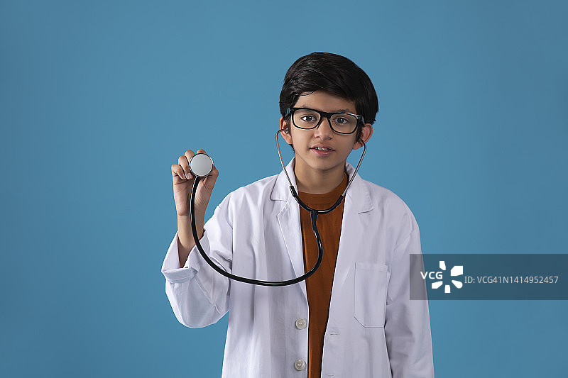 微笑的男孩的肖像与听诊器站在蓝色的背景图片素材