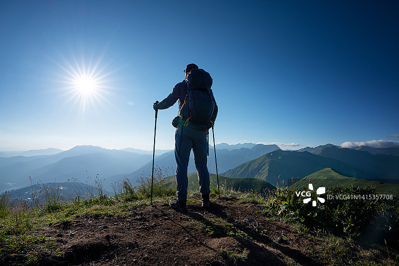 徒步旅行者独自站在日落时的山顶上，后景图片素材