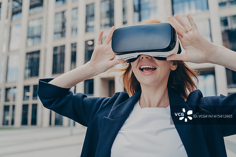 兴奋的女商人在户外用VR头盔探索虚拟现实图片素材