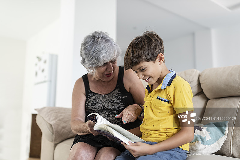 奶奶和孙子在家里的沙发上享受了一会儿阅读图片素材