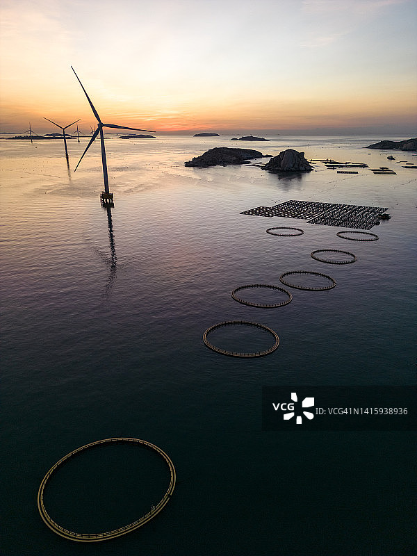 黄昏时海上风力涡轮机和圆形渔网的鸟瞰图图片素材