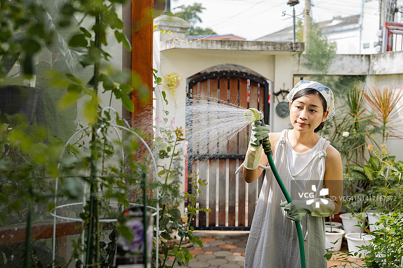 在后院给她的植物浇水。图片素材