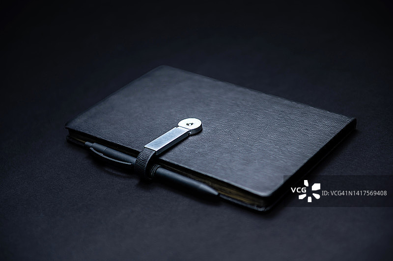 黑色记事本或笔记本与钢笔隔离在黑色背景，模型，拷贝空间图片素材