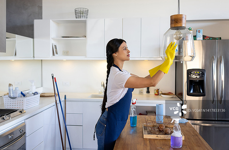 清洁工正在清洗一所房子厨房里的一盏灯图片素材