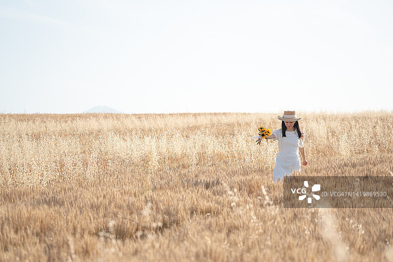 一个年轻的女人在金色的麦田里奔跑图片素材
