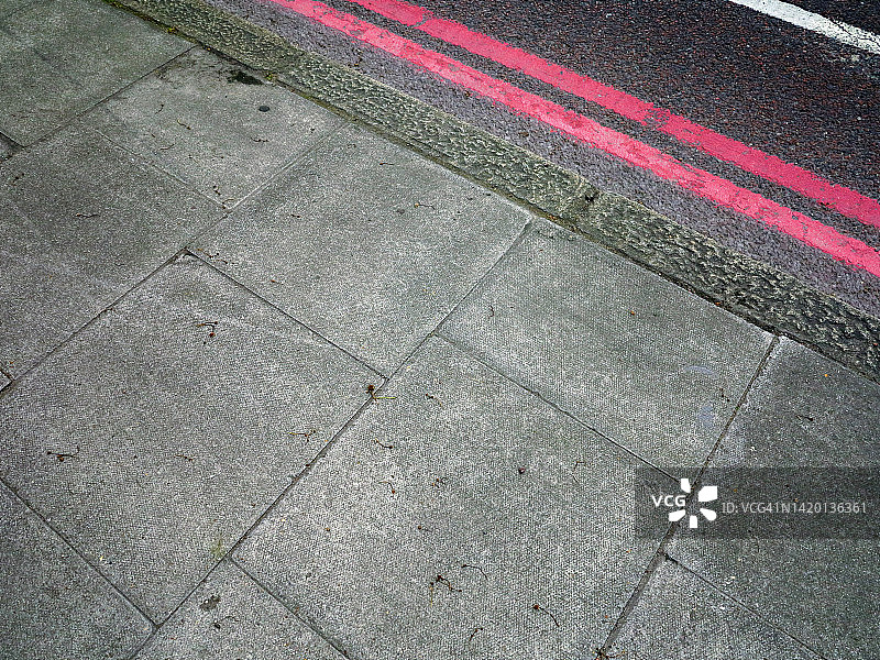英国伦敦，风化的灰色混凝土板人行道和红白相间的柏油路图片素材
