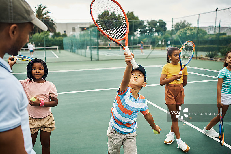 网球，孩子们和教练一起运动，孩子们和他们的团队在外面的运动场上训练和练习。小男孩和女孩为了健身、娱乐和健康而玩比赛或游戏图片素材
