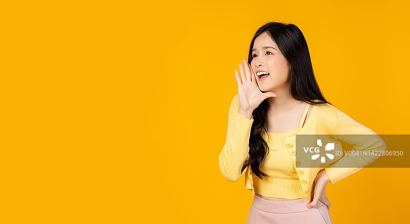 惊讶的快乐的亚洲妇女在兴奋地寻找复制空间表情丰富的面部表情展示产品美丽的女孩像一个告诉销售项目孤立在黄色背景复制空间图片素材