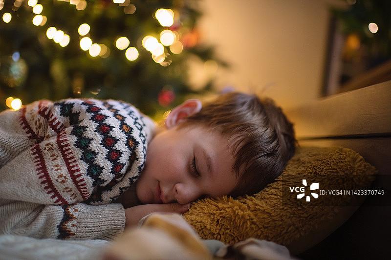 小男孩在圣诞树旁睡觉图片素材