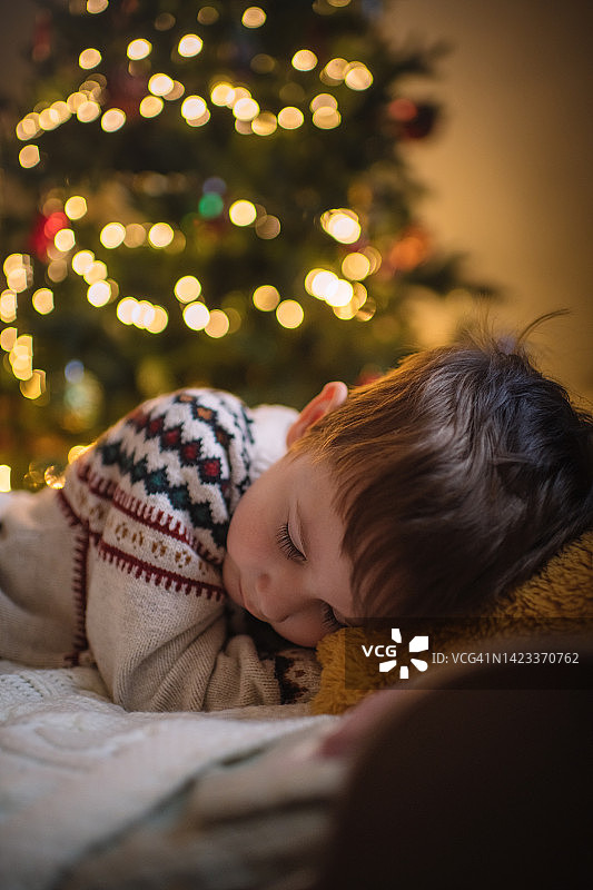 小男孩在圣诞树旁睡觉图片素材