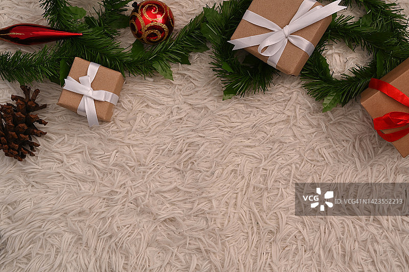 圣诞礼品盒和杉树树枝在白色毛皮地毯上。平铺，顶视图和复制空间的文本。图片素材