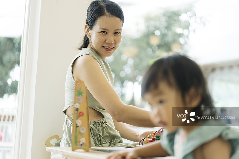 近距离拍摄积极情绪的亚洲母亲教女儿如何玩蒙特梭利玩具图片素材