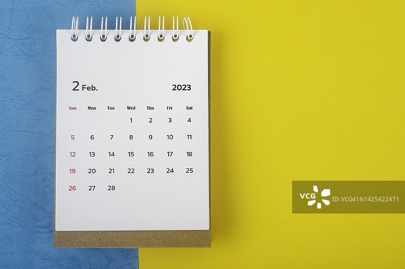 2023日历台:2月是组织者在双色纸背景上计划和提醒的月份。图片素材