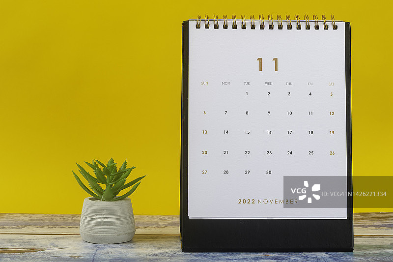 2022年日历台:11月是组织者的一个月，在黄色纸背景的室内植物的计划和截止日期。图片素材