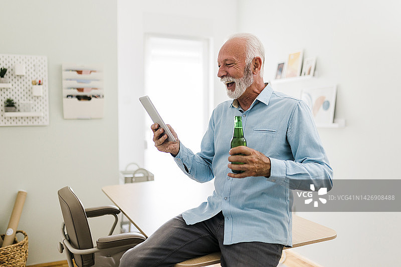 老人一边喝着啤酒，一边用平板电脑进行视频通话图片素材