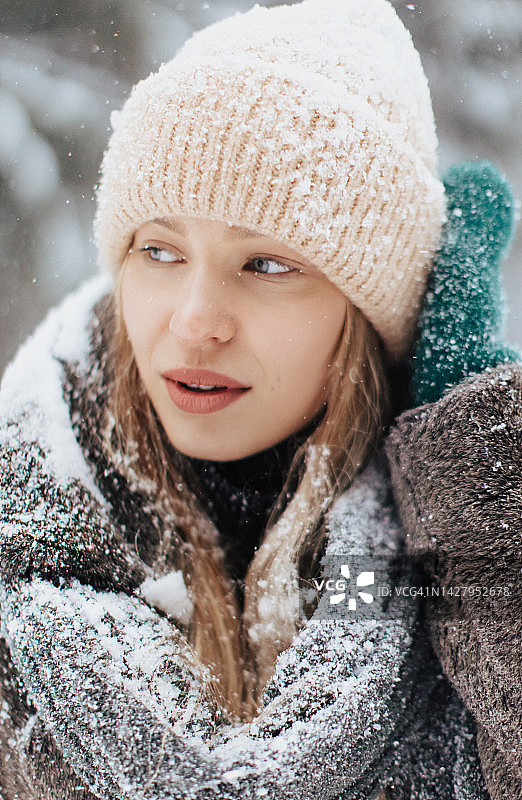 冬天，快乐的年轻女子在大自然的雪花下看着相机图片素材