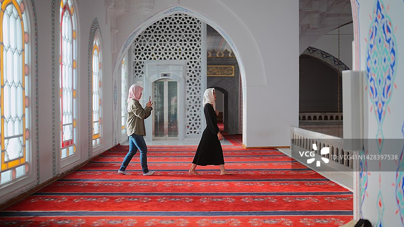 年轻的女游客和社交媒体影响者在旅行中访问清真寺时被拍摄和拍摄图片素材