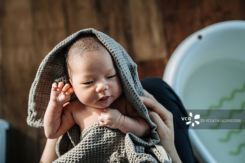 高角度拍摄一个充满爱的亚洲母亲抱着襁褓中的新生儿，擦干刚洗完澡的女婴。新的生活。爱与关怀概念图片素材