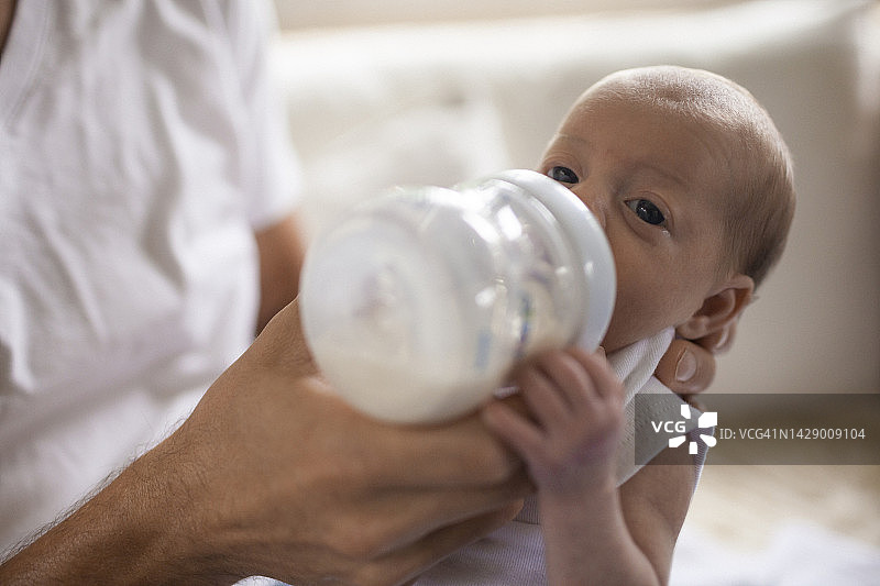 一位父亲用奶瓶喂他刚出生的宝宝图片素材