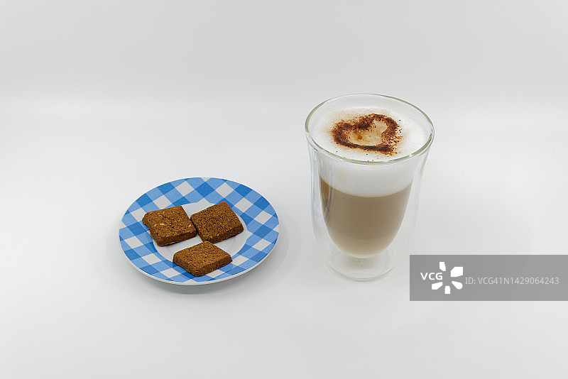 牛奶咖啡与大量的泡沫和巧克力心，蓝和白色格子盘方形饼干，白色背景，甜点与爱图片素材