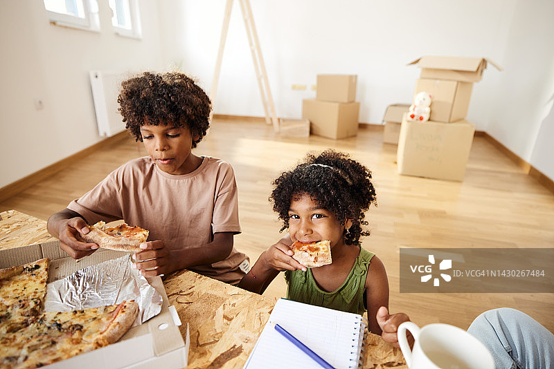 黑人小孩在新公寓吃披萨。图片素材