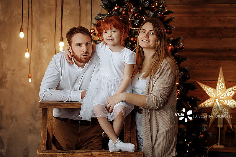 美丽幸福的一家人正坐在靠近圣诞树的楼梯上图片素材