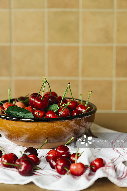 新鲜的樱桃在陶瓷碗上红色条纹餐巾新鲜的甜红色樱桃在木碗-健康的生活方式和有机生物水果的概念-复制空间在顶部的文字图片素材