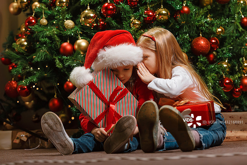 孩子们分享关于圣诞老人在圣诞树下发现的珍贵礼物的秘密图片素材