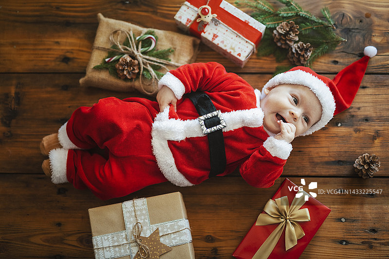 可爱的照片，穿着圣诞老人服装的婴儿躺在圣诞礼物中。图片素材