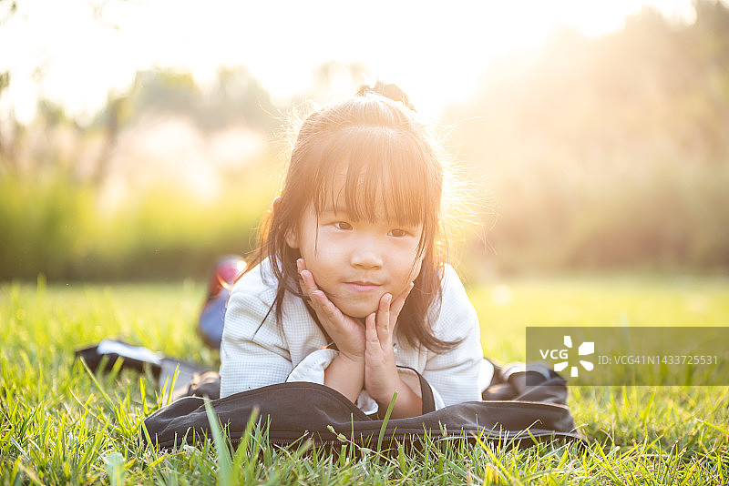 一个微笑的小女孩躺在绿色的草地上的画像图片素材