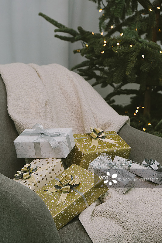 礼品盒上的椅子附近的圣诞树与电花环。图片素材
