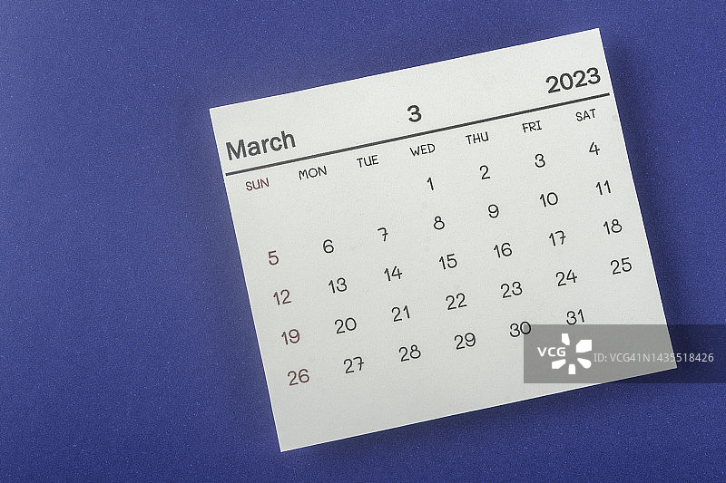 2023年日历桌面俯视图:3月是组织者计划的一个月，蓝纸背景是截止日期。图片素材