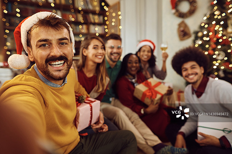 快乐的男人在圣诞节和他的朋友在家里自拍。图片素材