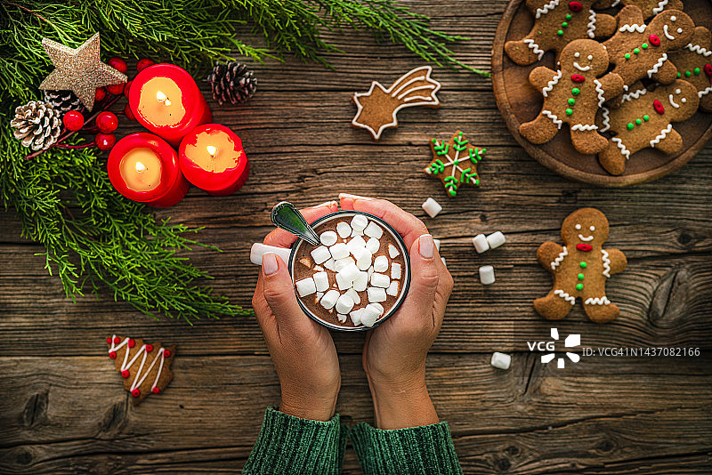 手拿圣诞热巧克力杯与棉花糖在乡村的桌子上图片素材