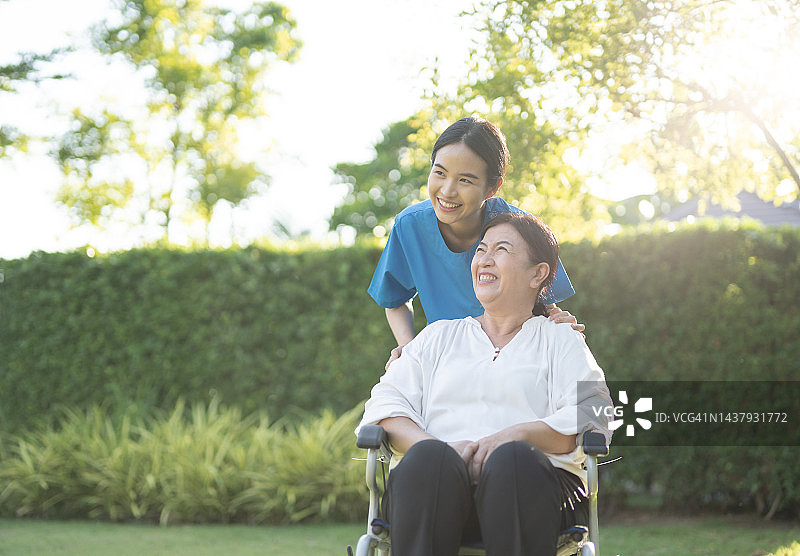 亚裔女护士在家中协助轮椅上的老年女病人幸福情绪图片素材