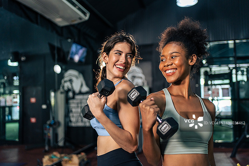 拉丁裔和非洲裔运动妇女在体育场锻炼和增肌。积极强壮美丽适合运动员女孩在运动服锻炼举重哑铃手臂和保健在健身俱乐部。图片素材