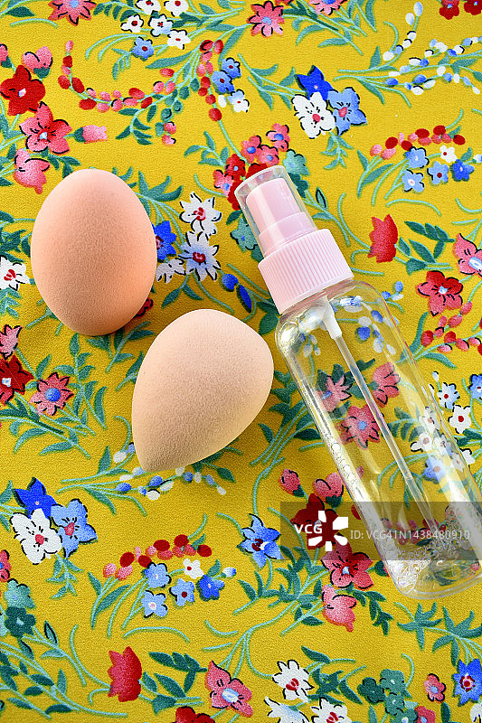 化妆海绵和化妆瓶在花的背景图片素材