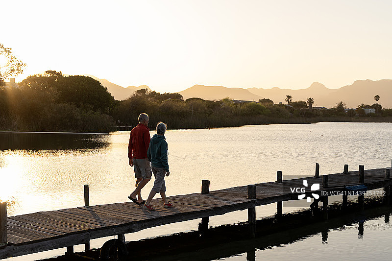 老夫妇在日落时分走在码头上图片素材