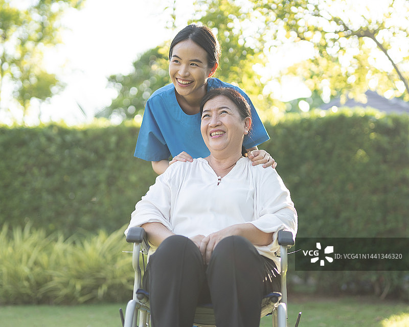 亚裔女护士在家中协助轮椅上的老年女病人幸福情绪图片素材