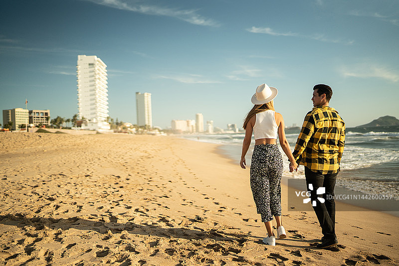 一对年轻夫妇沿着海滩散步图片素材