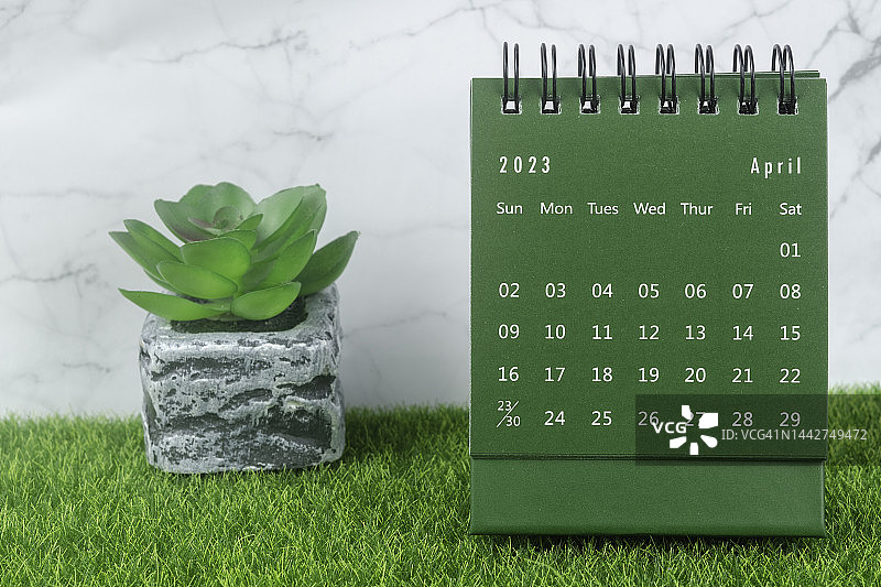 日历桌2023:4月是组织者计划的一个月，在大理石混凝土背景下的室内植物。图片素材