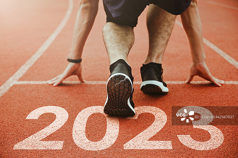 2023年新年快乐，2023年象征着新的一年的开始。一名男子正准备在刻着2023年的跑道上跑步。成功的目标。为新年做准备图片素材