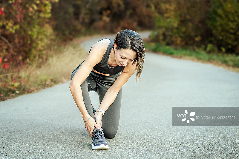 年轻健康的女子在慢跑时脚踝受伤图片素材